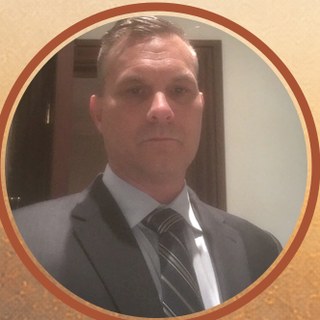 Portrait of author Kevin L. Lewis in a gray suit and tie